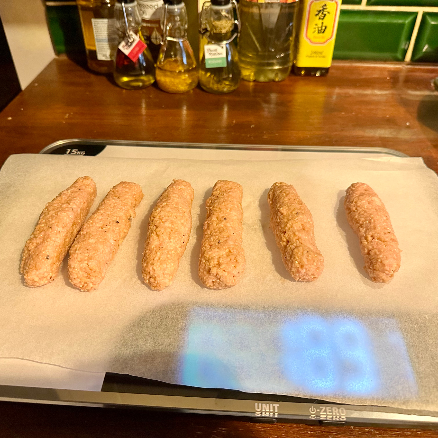 Six pink and grainy vegan sausages which have been roughly shaped from Sosmix