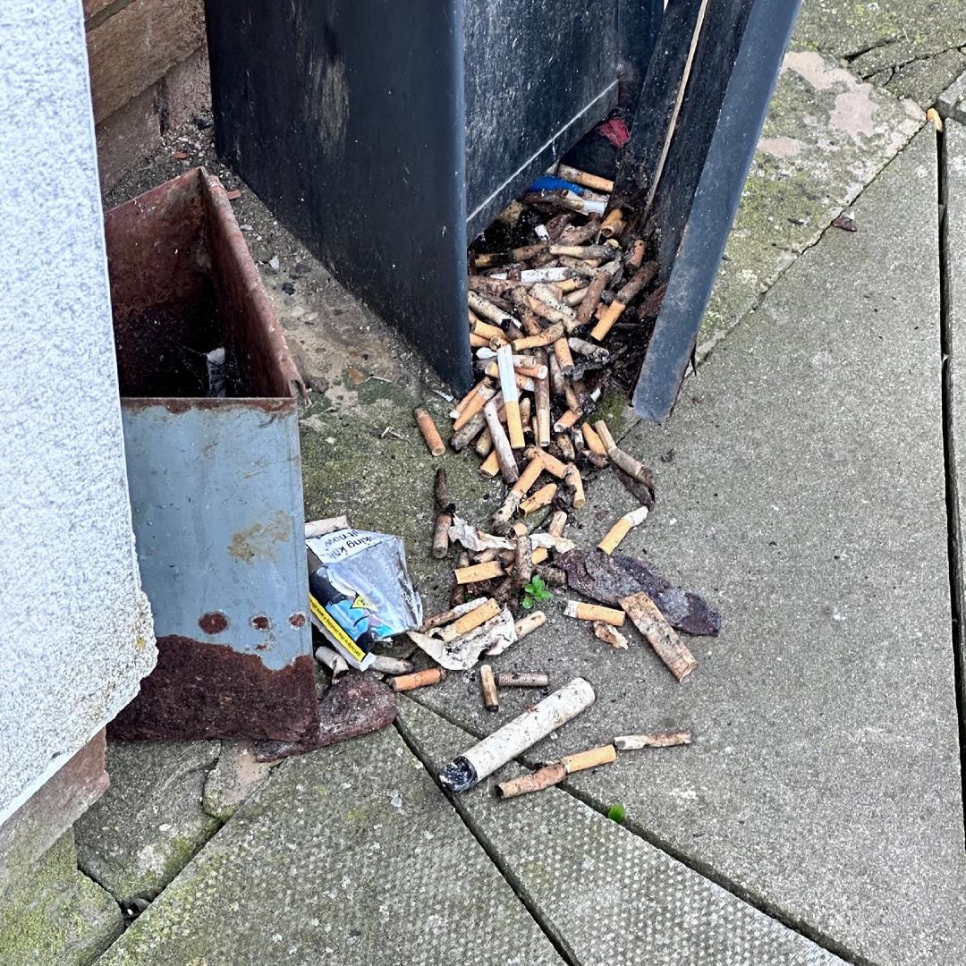 A large ash tray which has been pulled away from the wall revealing heaps of stale cigarettes