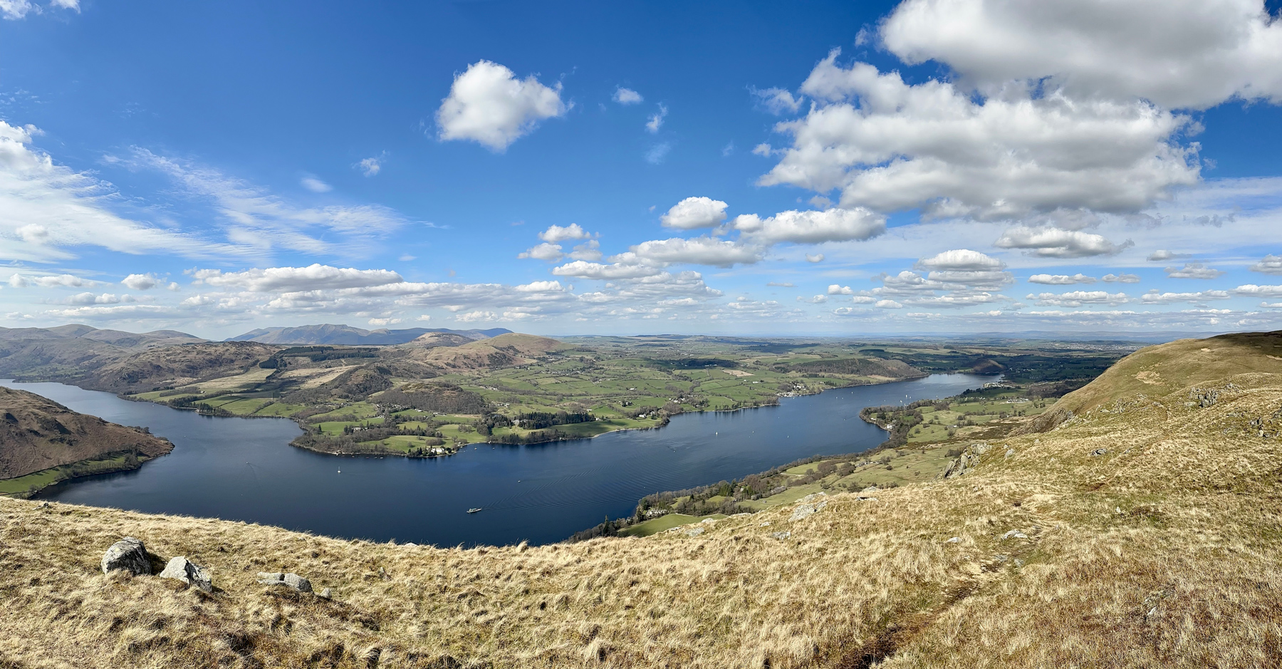 A panoramic view over Ullswater Lake from the top of our walk. The sun is shining and the sky is blue.