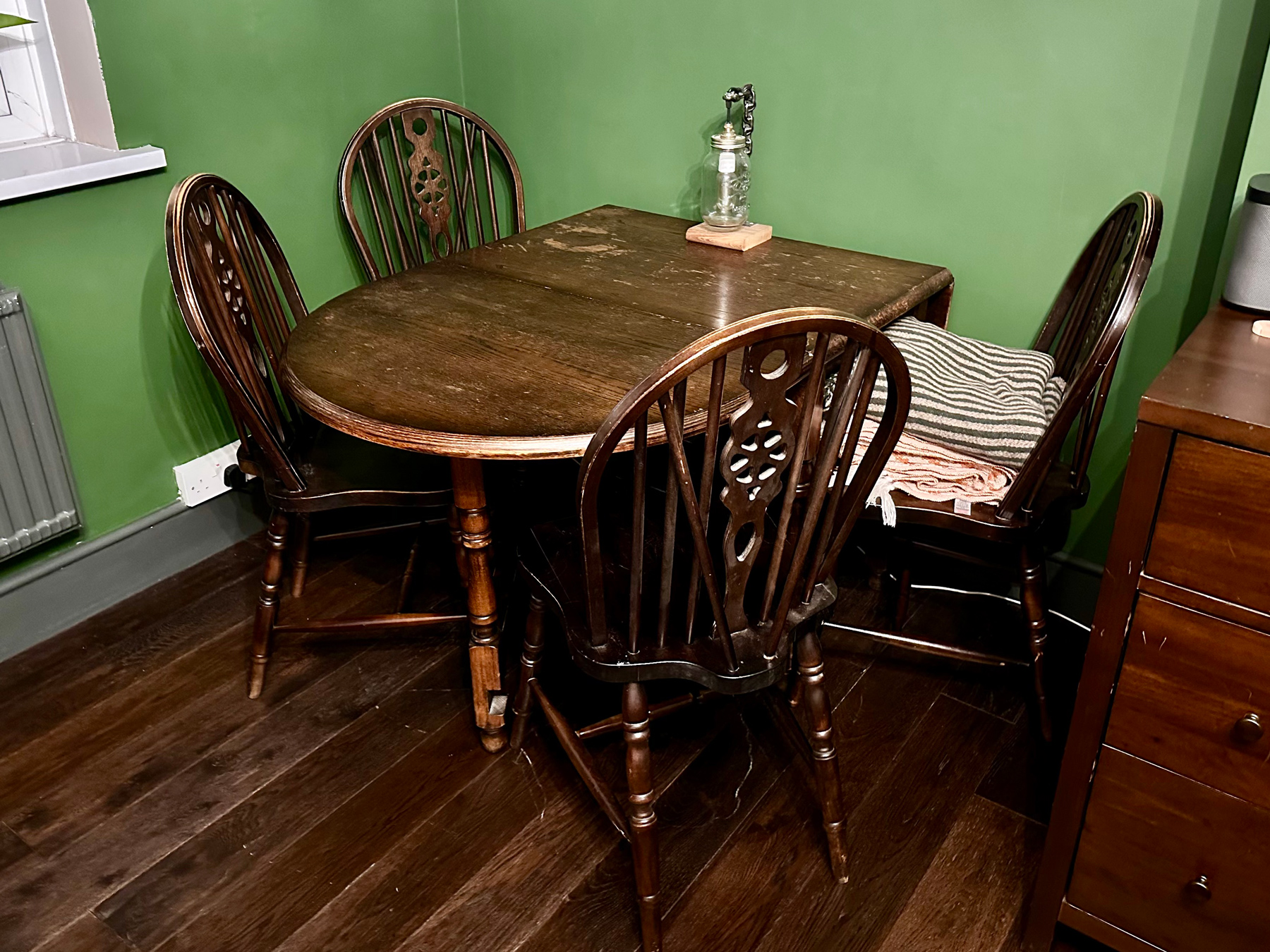A dark wood drop-leaf table with four chairs, set into an alcove