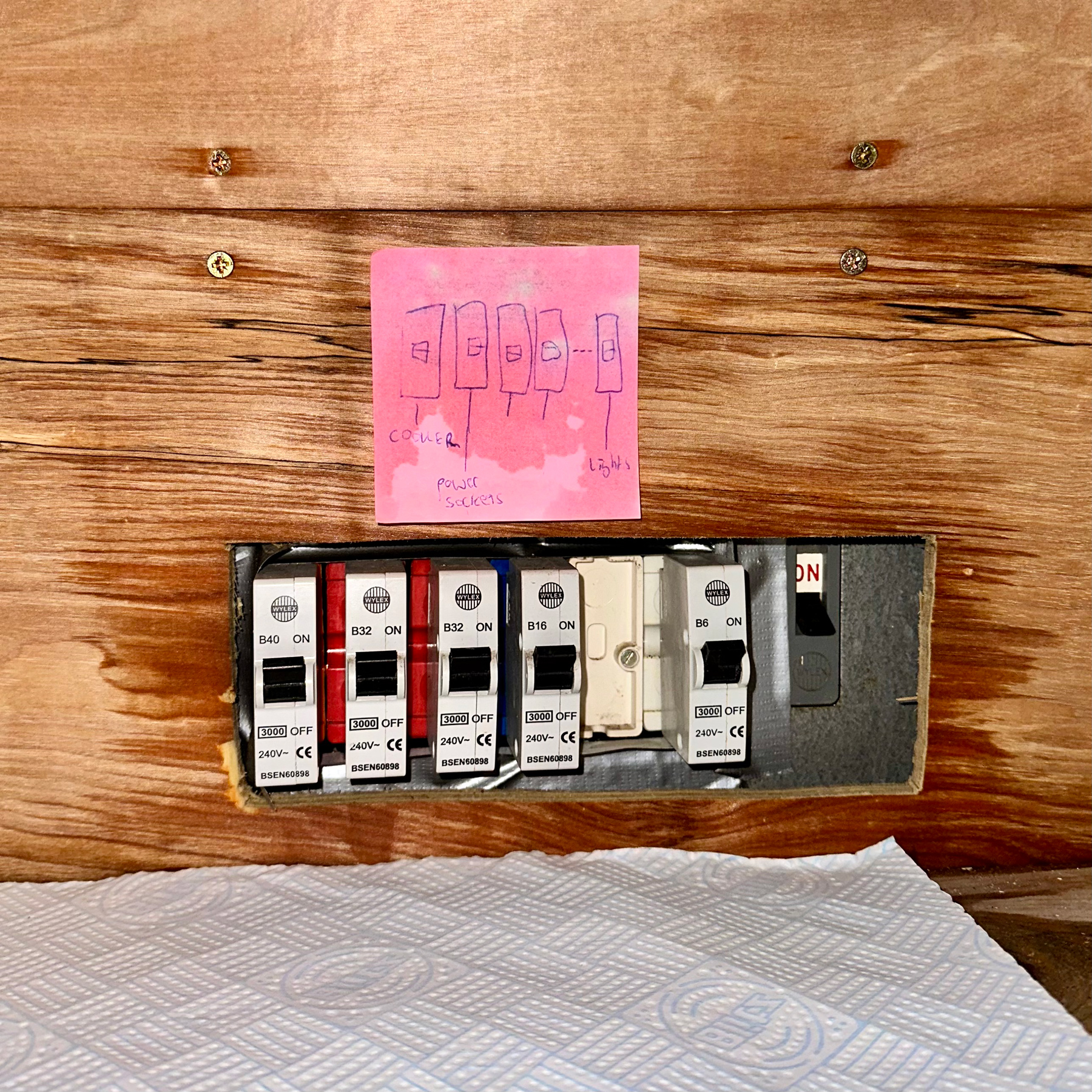 Some electrical switches surrounded by slightly damp wood and a post-it note that's clearly seen some water recently