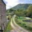 A view down a dirt track weaving between hills, with part of a French château in the foreground