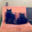 Two small black cats sat on a pink chair together