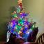 Two cute black cats sat next to a Christmas tree