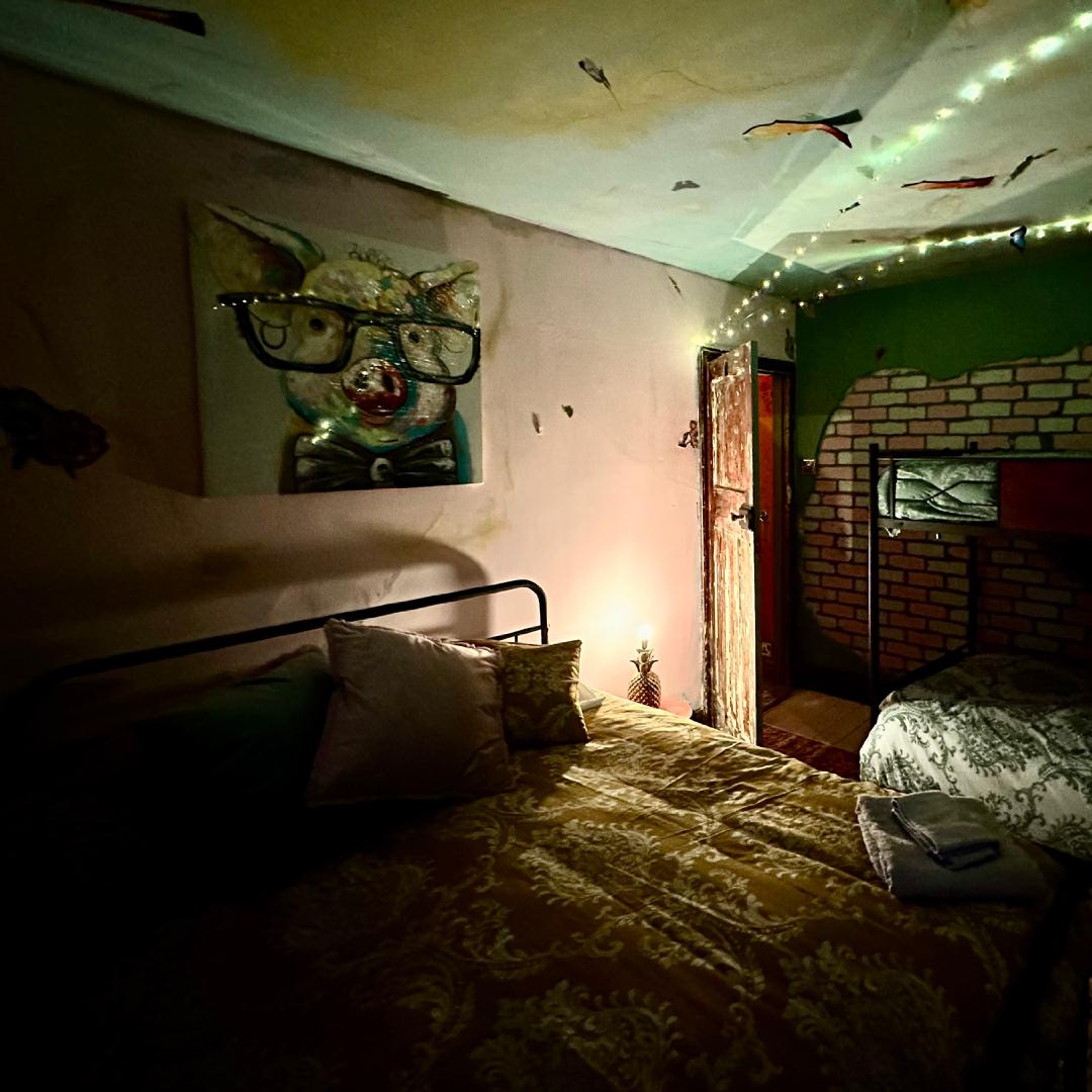 A bedroom adorned with fairy lights, a painting of a pig, with exposed brick in odd patches