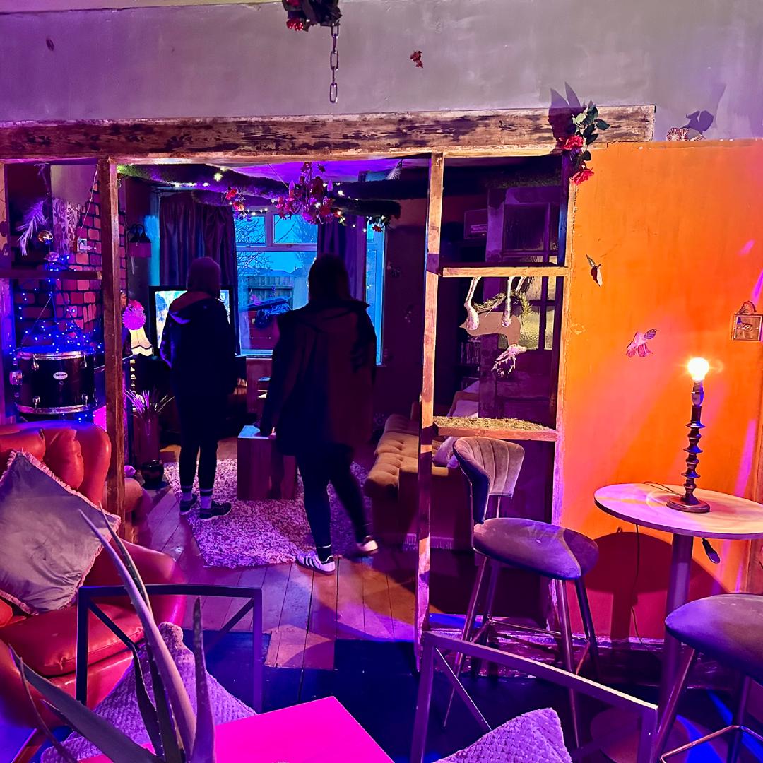 A dining room lit from lots of different angles by coloured lights, ornaments are dotted around and decorations stapled to the walls