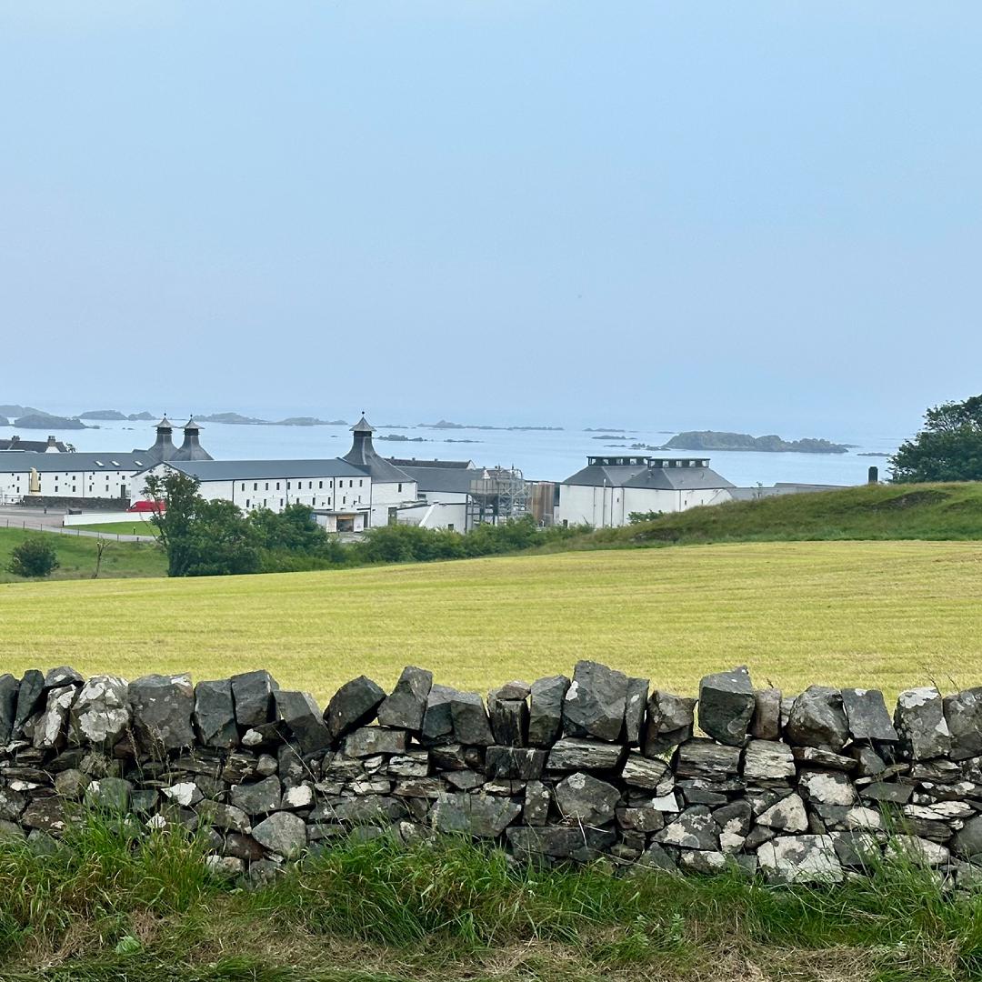 A view from the road down to the Ardbeg distillery complex. It's a sprawl of white buildings with a rocky bay beyond