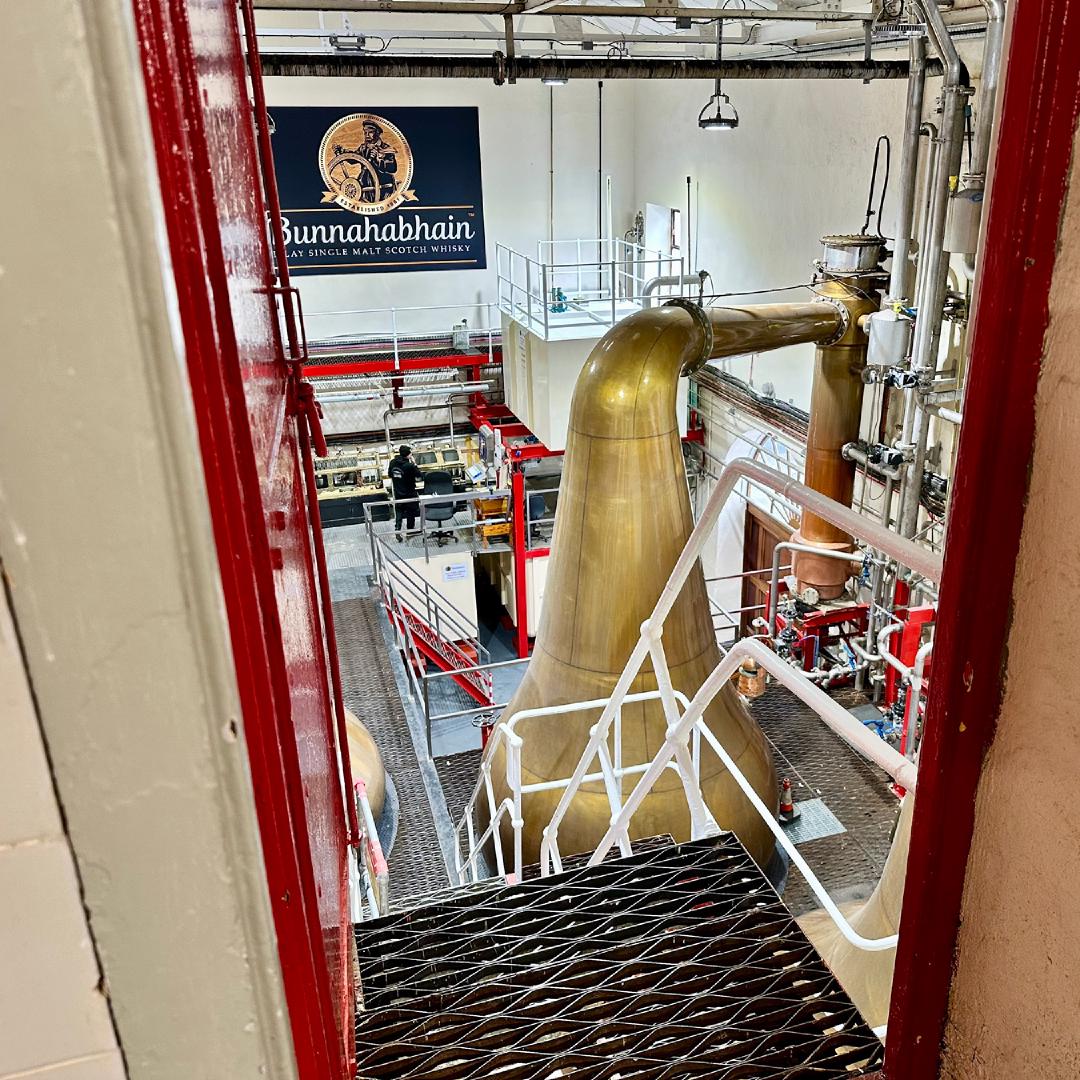 A view through a doorway of several large copper stills for distilling whisky