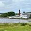 A view of the Lagavulin distillery from the coast, white brick buildings with a painted black sign and a bright red chimney