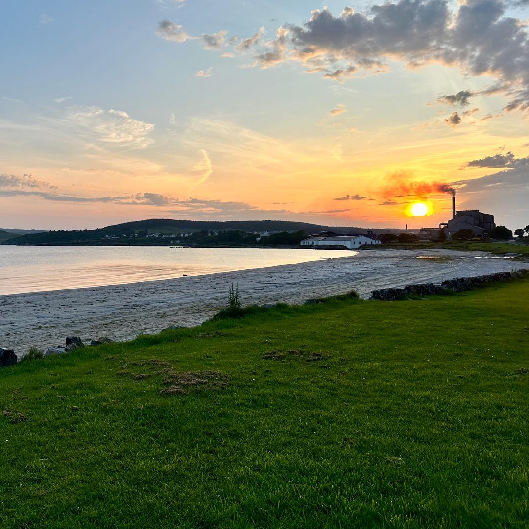 An orange sky lighting a sandy beach, with a factory – the maltings – spewing a streak of smoke across the setting sun