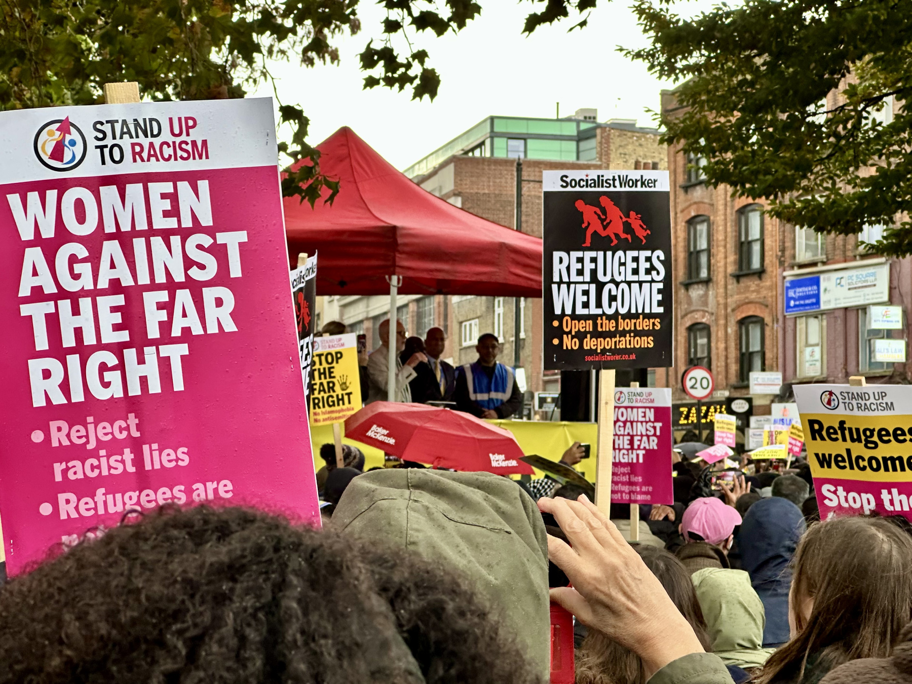 Large crowds gathered in Whitechapel holding anti-racist placards, watching Jeremy Corbyn deliver a speech