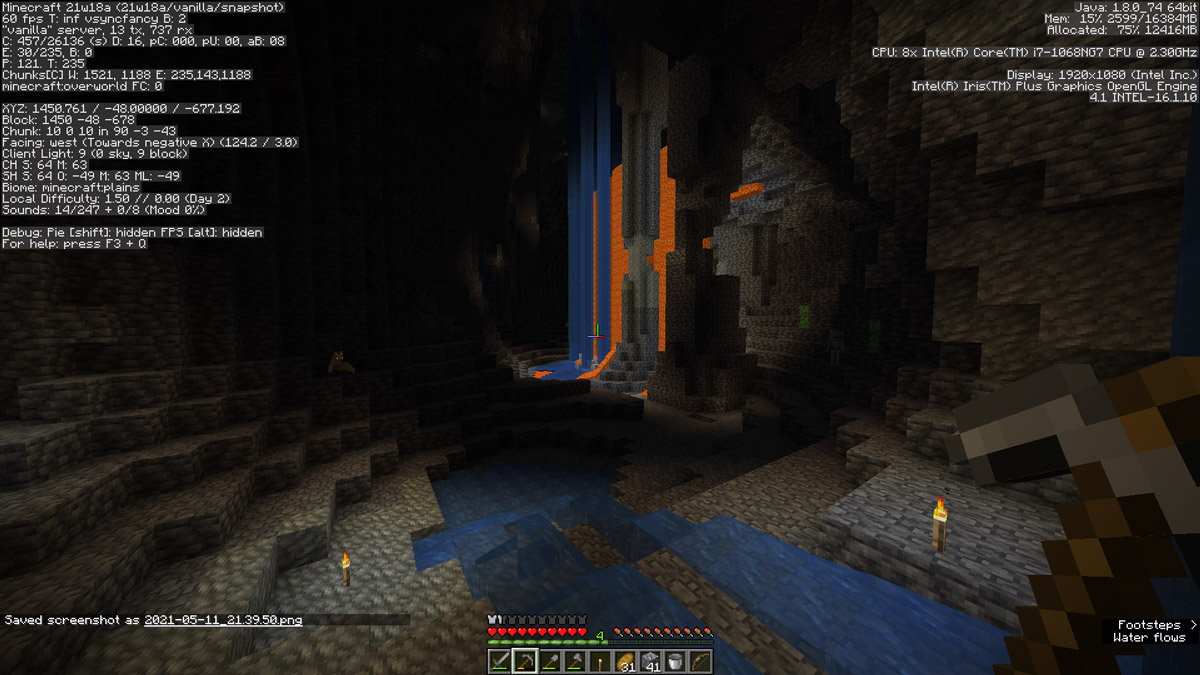 A large cave system in Minecraft, with pillars of rock and water and lava falls cascading from the ceiling.