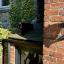 A black cat stuck on a hot slate roof looking grumpy about it
