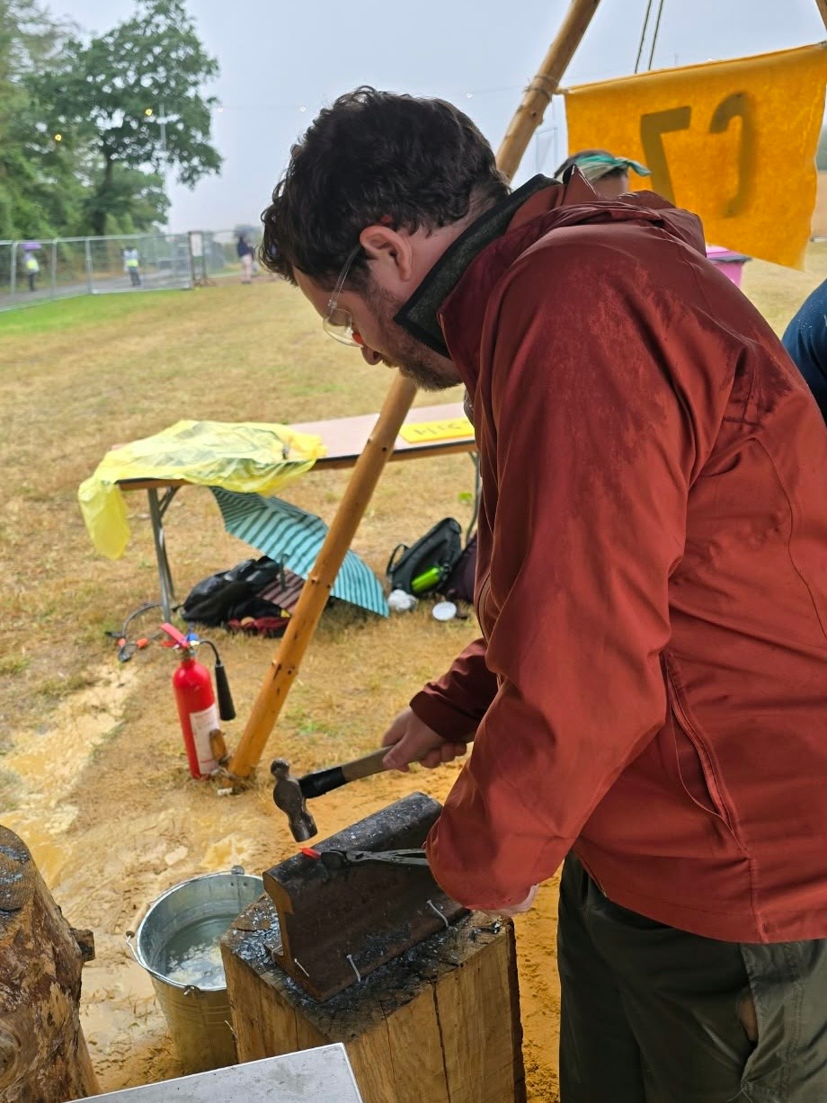 Me stood over an anvil hammering a strip of red hot metal