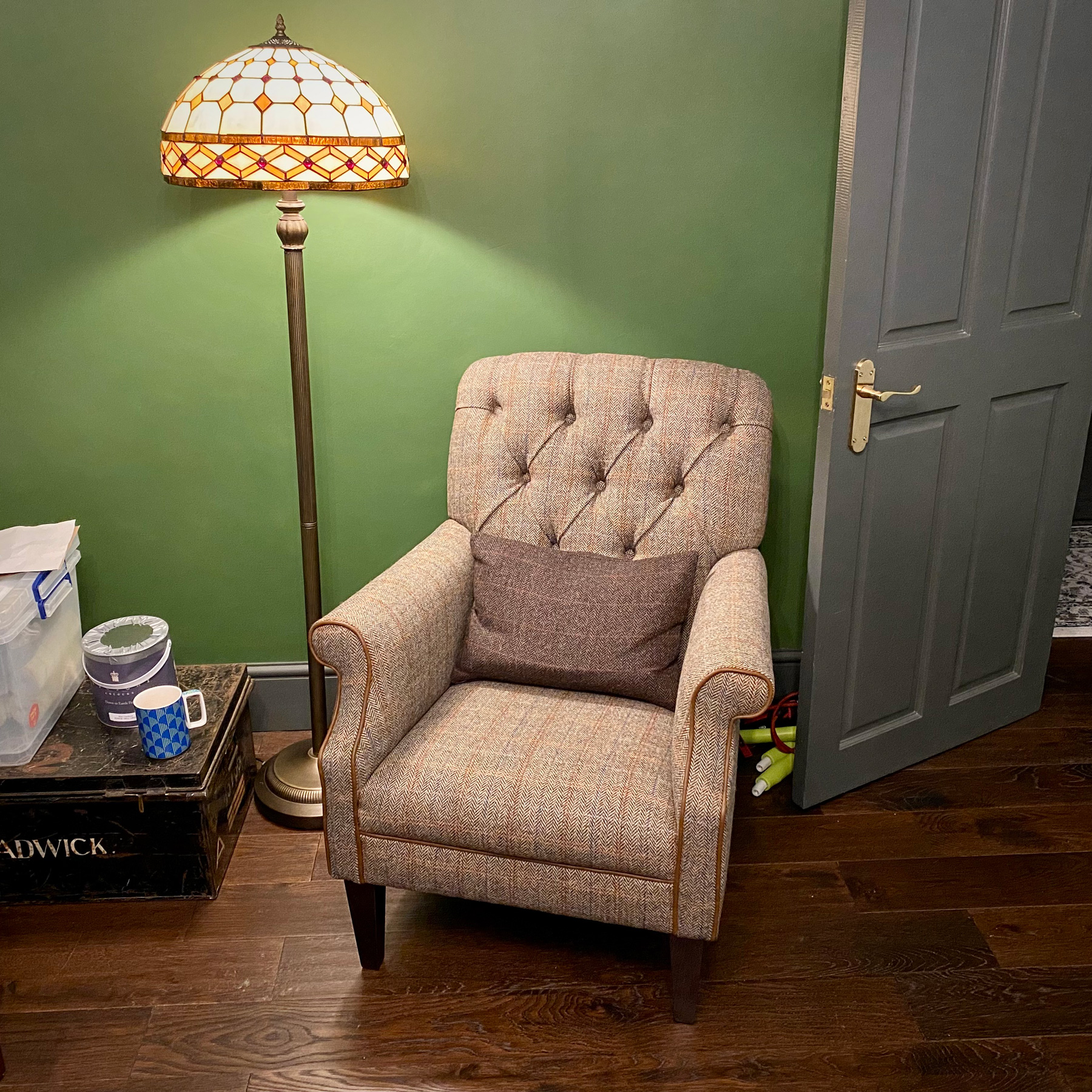 A cosy-looking tweed armchair lit by a tall lamp