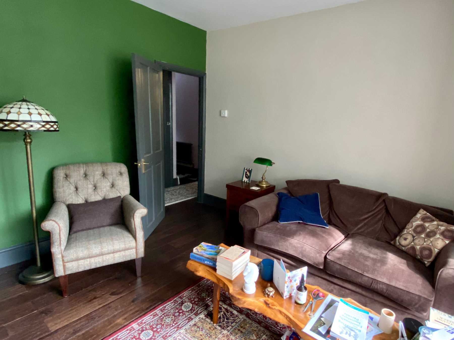 The corner of a living room with green on one wall and beige cream on the other